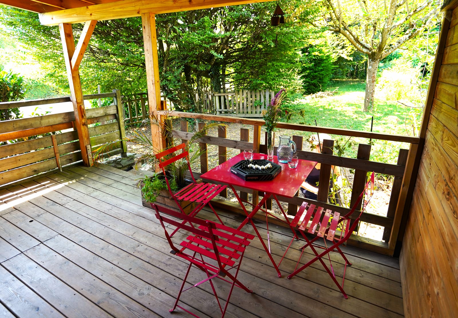 Terrasse couverte avec table et chaises Fermob rouges